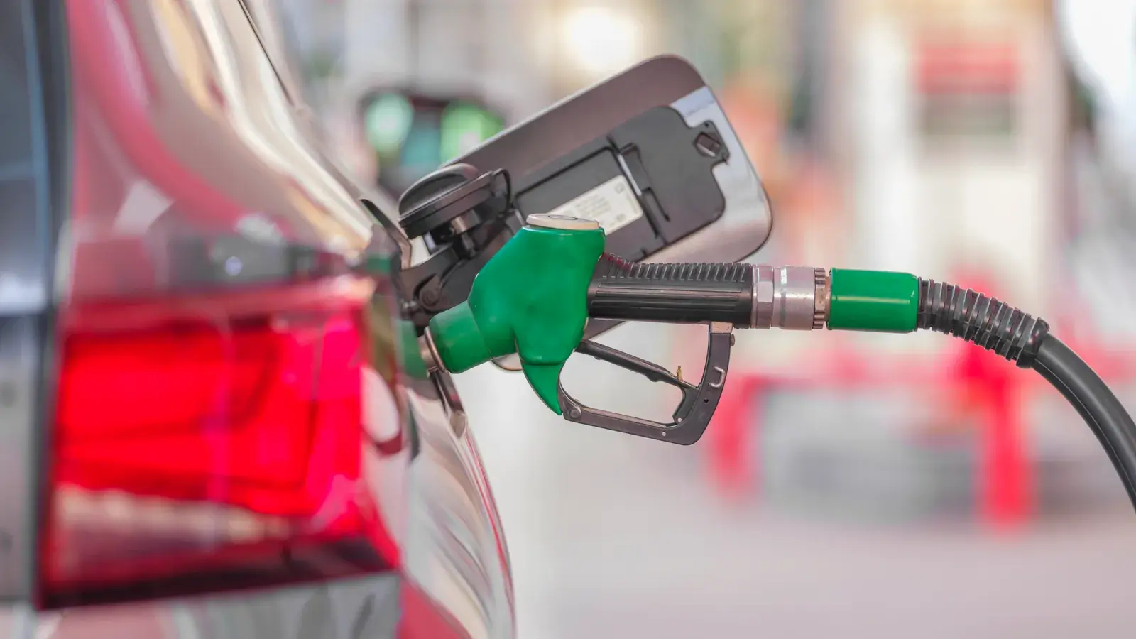 Green fuel pump nozzle inserted into a car's fuel tank opening