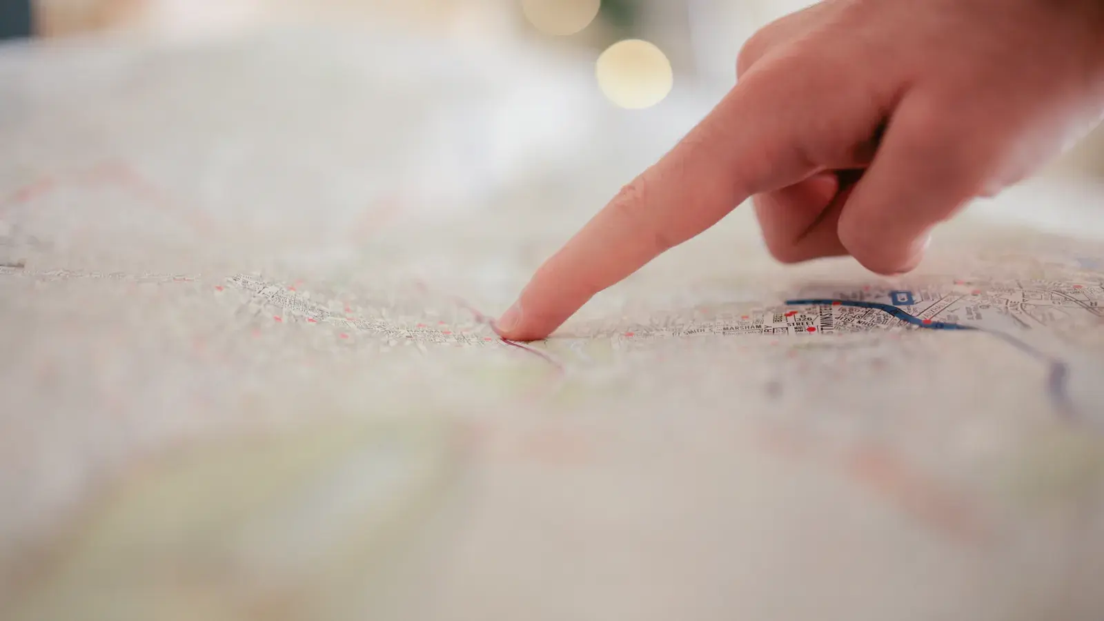 A finger pointing at a detailed map showing roads and city locations