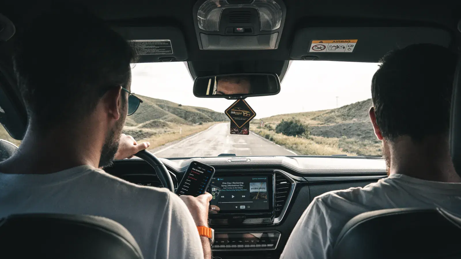 Two men driving through a scenic landscape using a cellphone e4e468