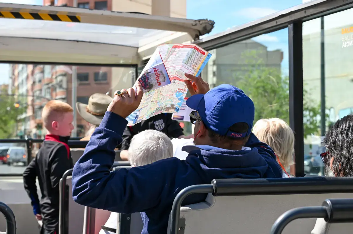 Tourists on an open-top bus holding and reading a colorful city map while sightseeing