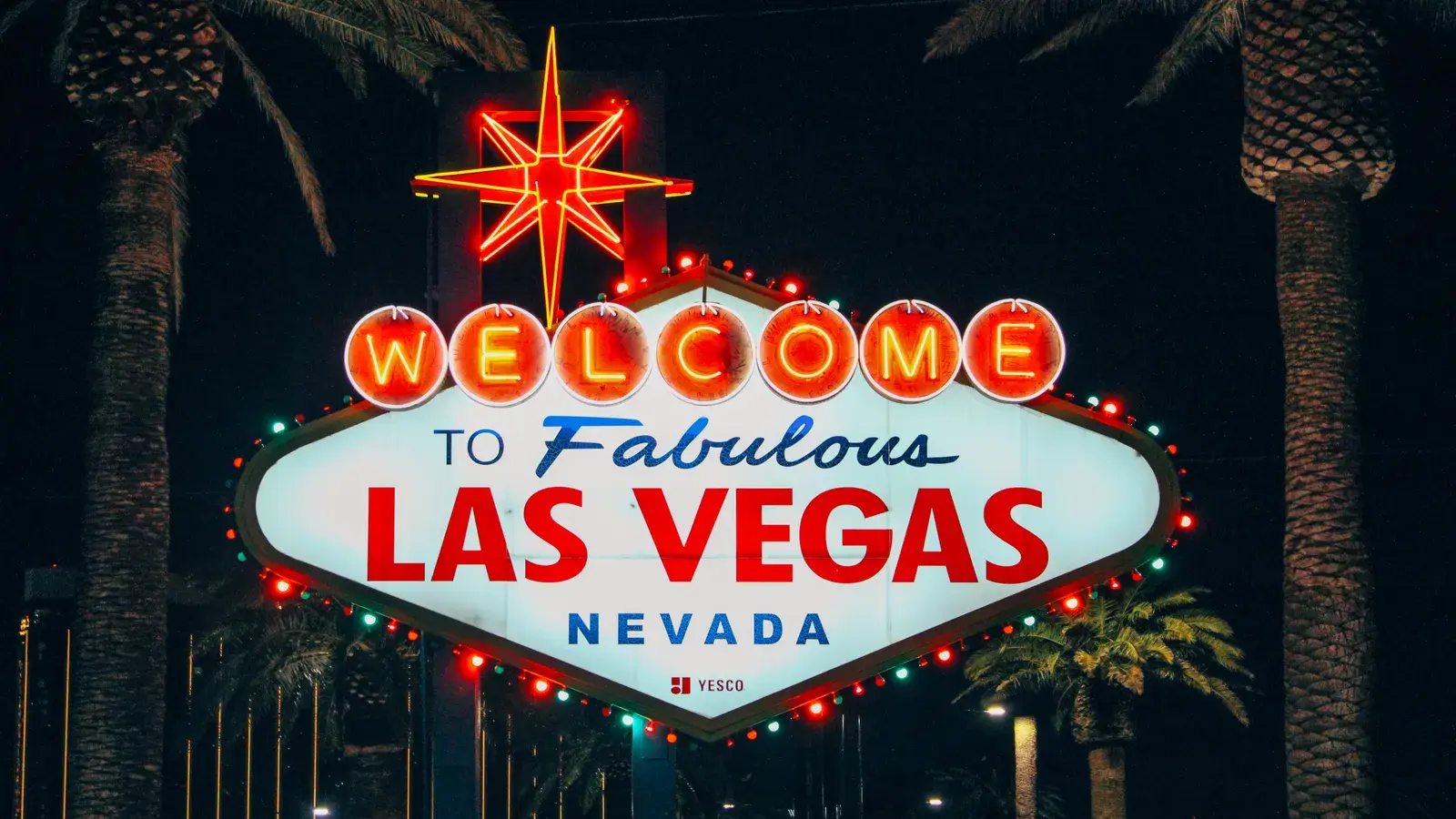 The iconic Welcome to Fabulous Las Vegas sign illuminated at night with a red star on top and palm trees flanking both sides
